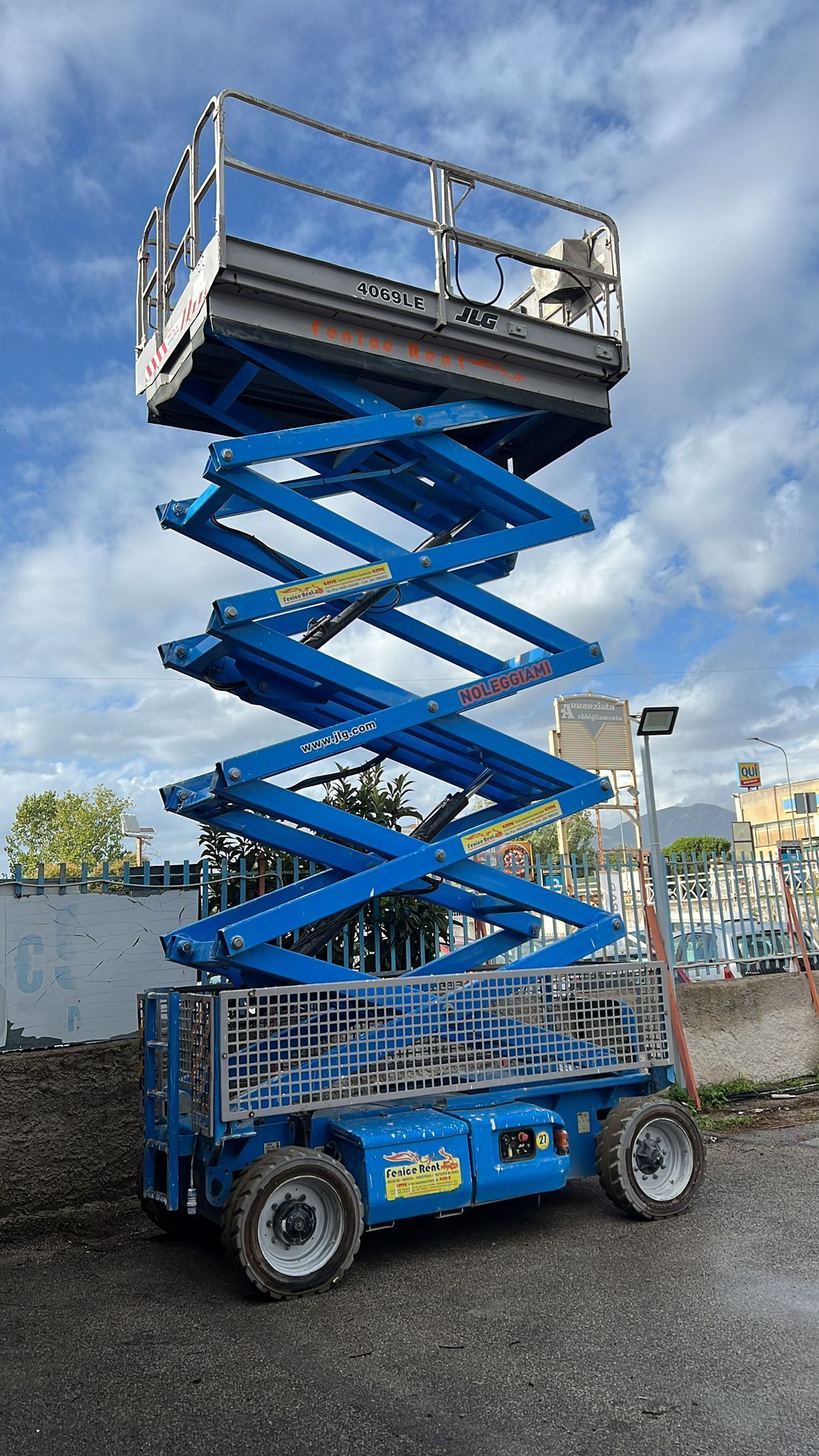 Piattaforma aerea blu sollevata in alto, all'aperto, vicino agli edifici.