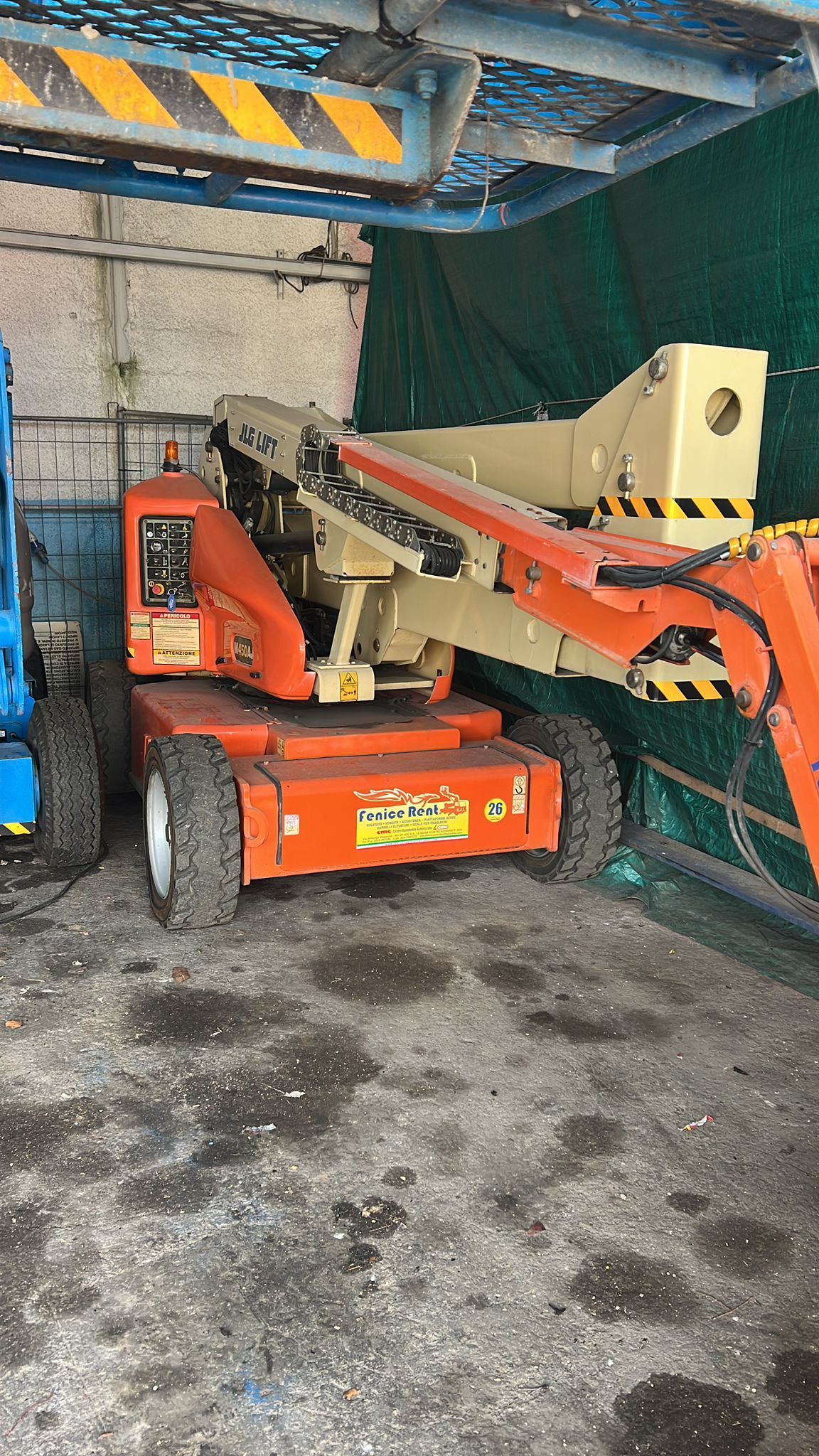 Piattaforma aerea articolata arancione e marrone chiaro in un magazzino.