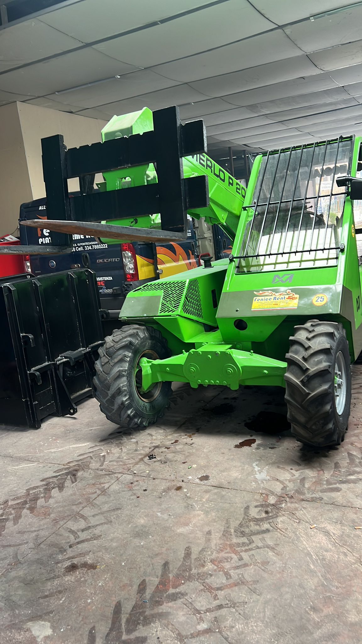 Caricatore compatto verde con accessori in un magazzino.