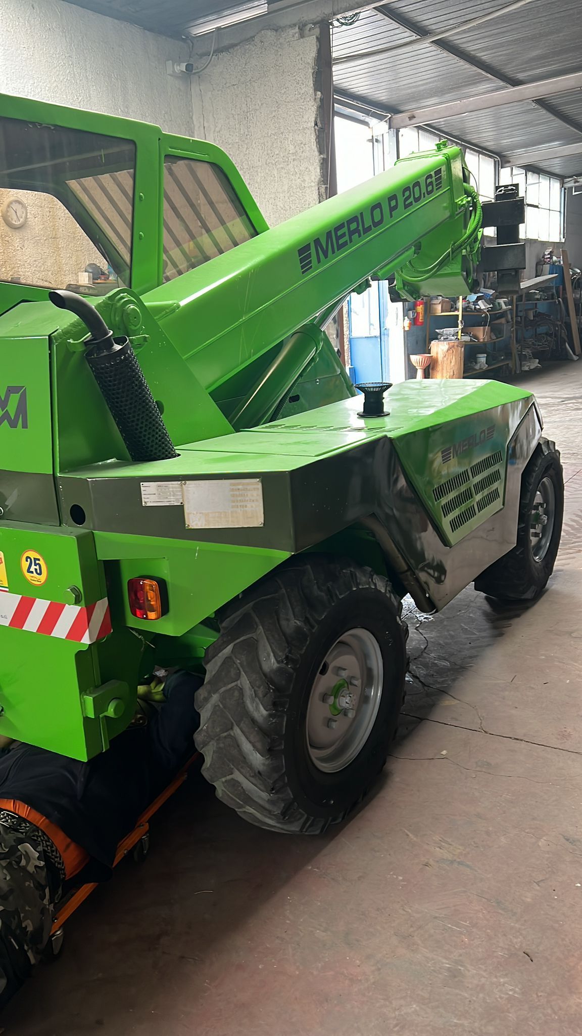 Sollevatore telescopico Merlo verde in un magazzino.