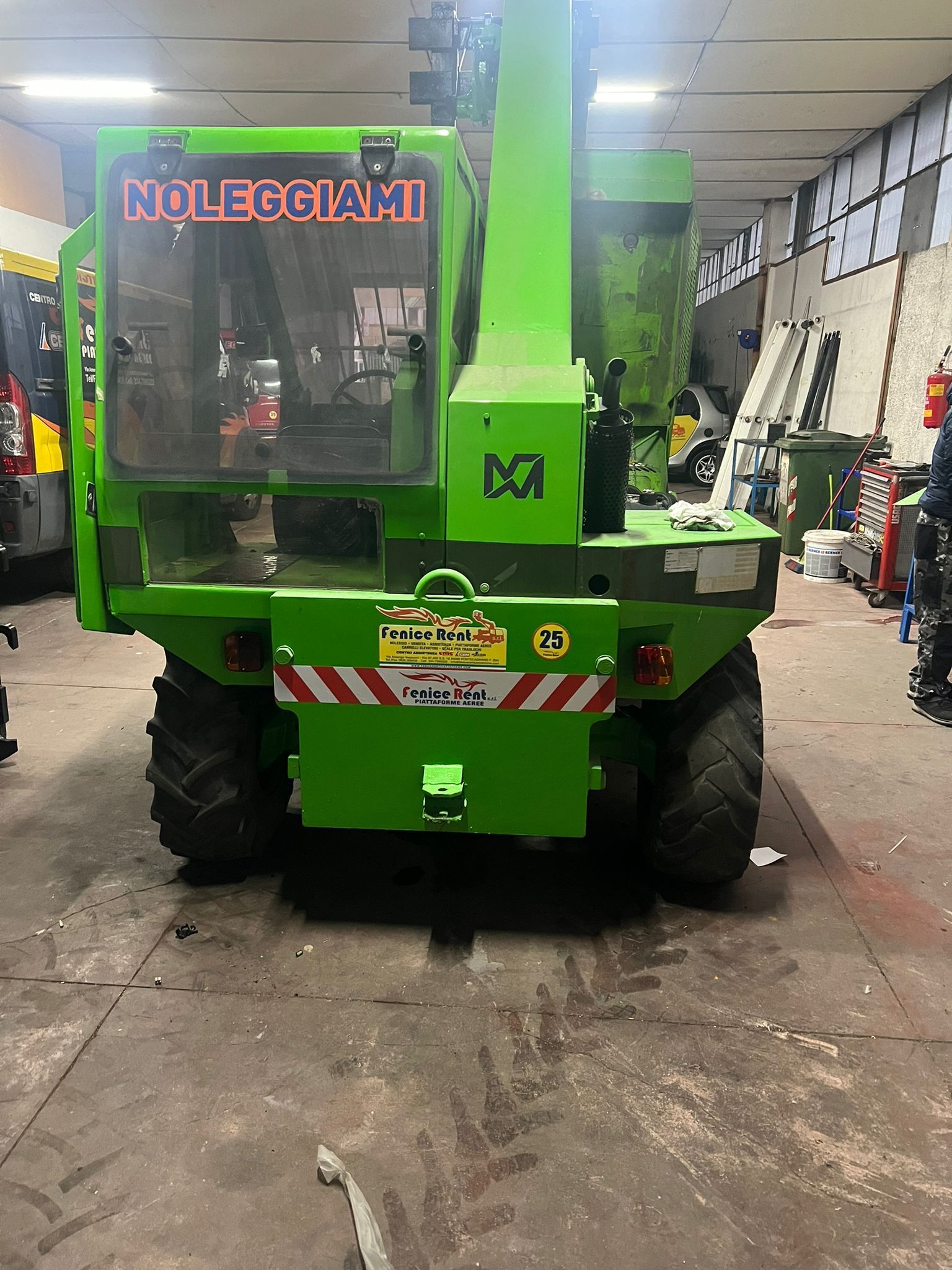 Sollevatore telescopico verde in un garage, con la scritta