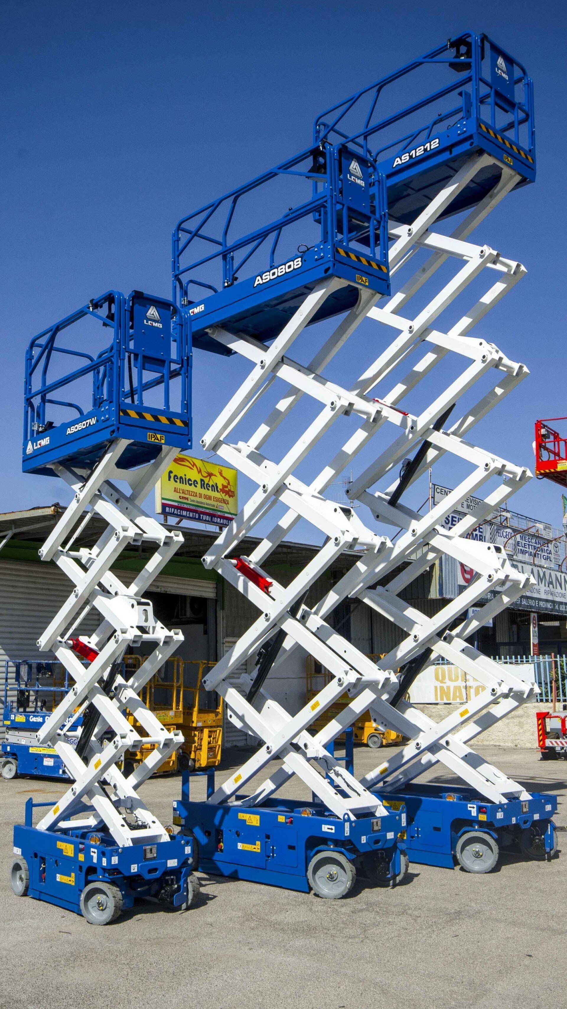 Tre piattaforme aeree blu di diverse dimensioni in un cantiere edile, pronte all'uso.