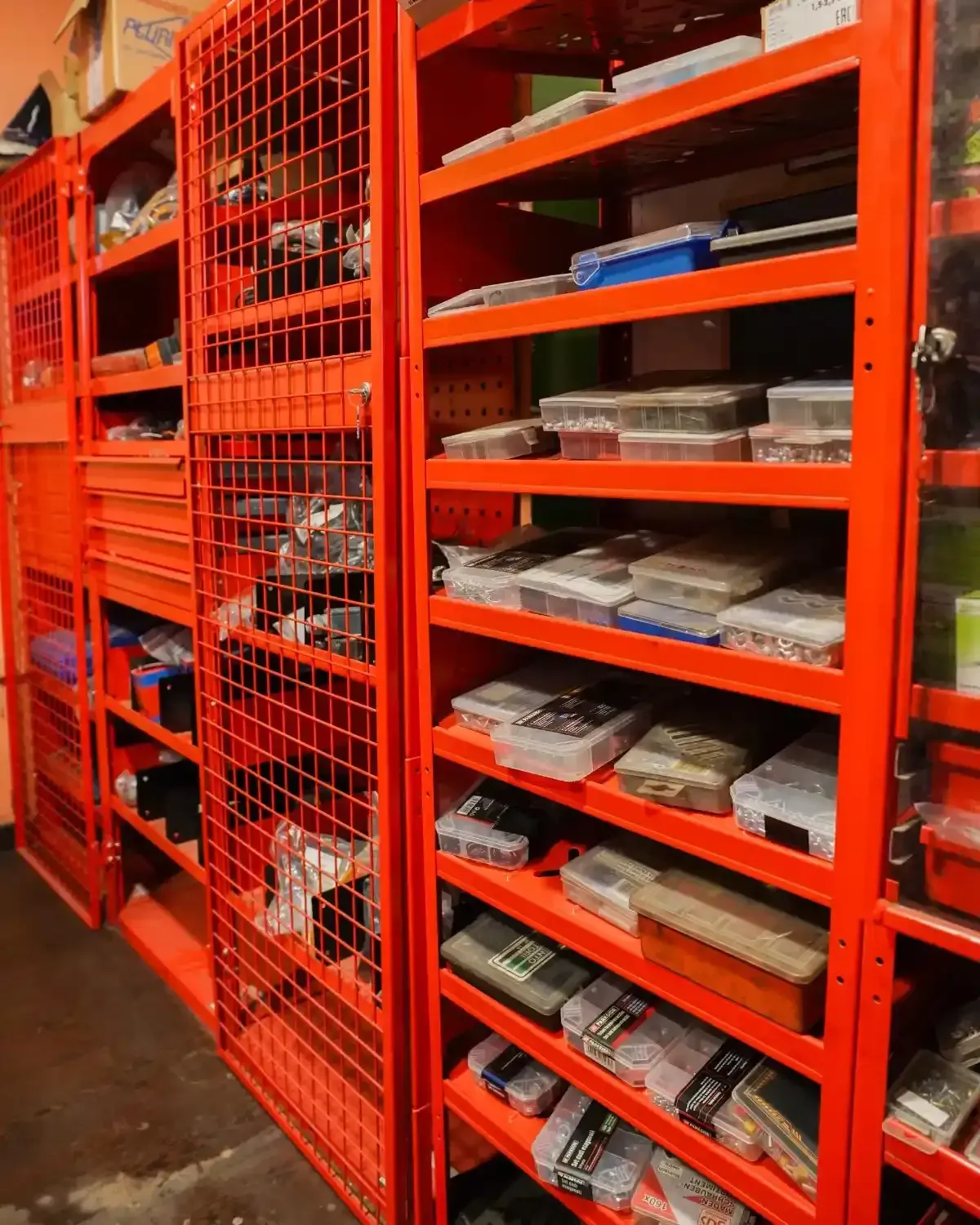 Scaffali di metallo rosso pieni di scatole e attrezzi in un'officina.