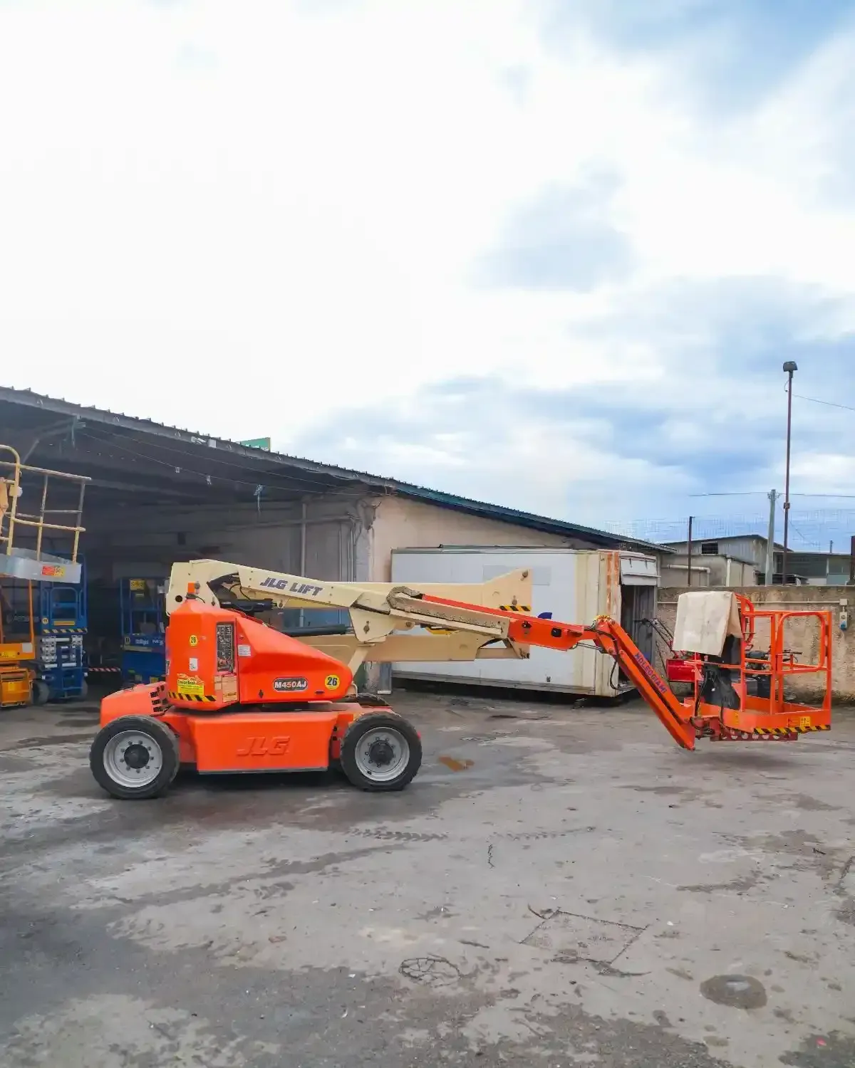 Ascensore aereo arancione che si estende verso un edificio beige in una giornata nuvolosa.