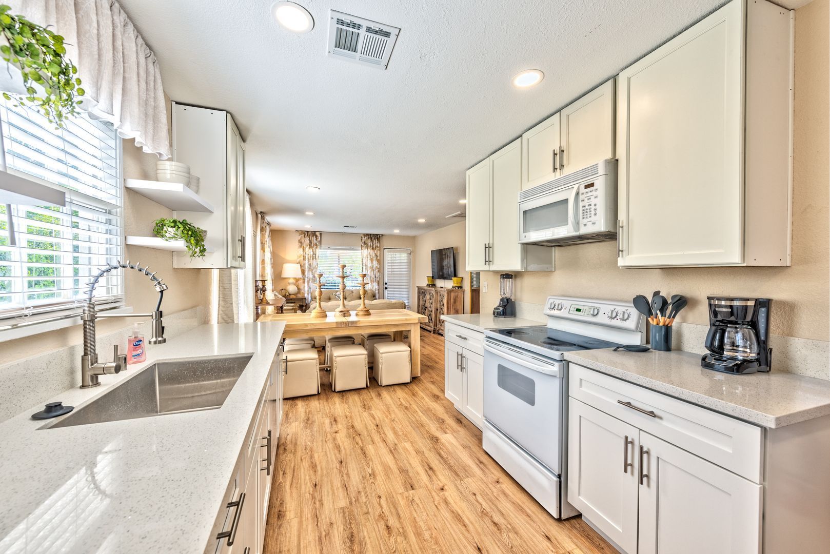 A kitchen with white cabinets , a stove , a sink , and a microwave.
