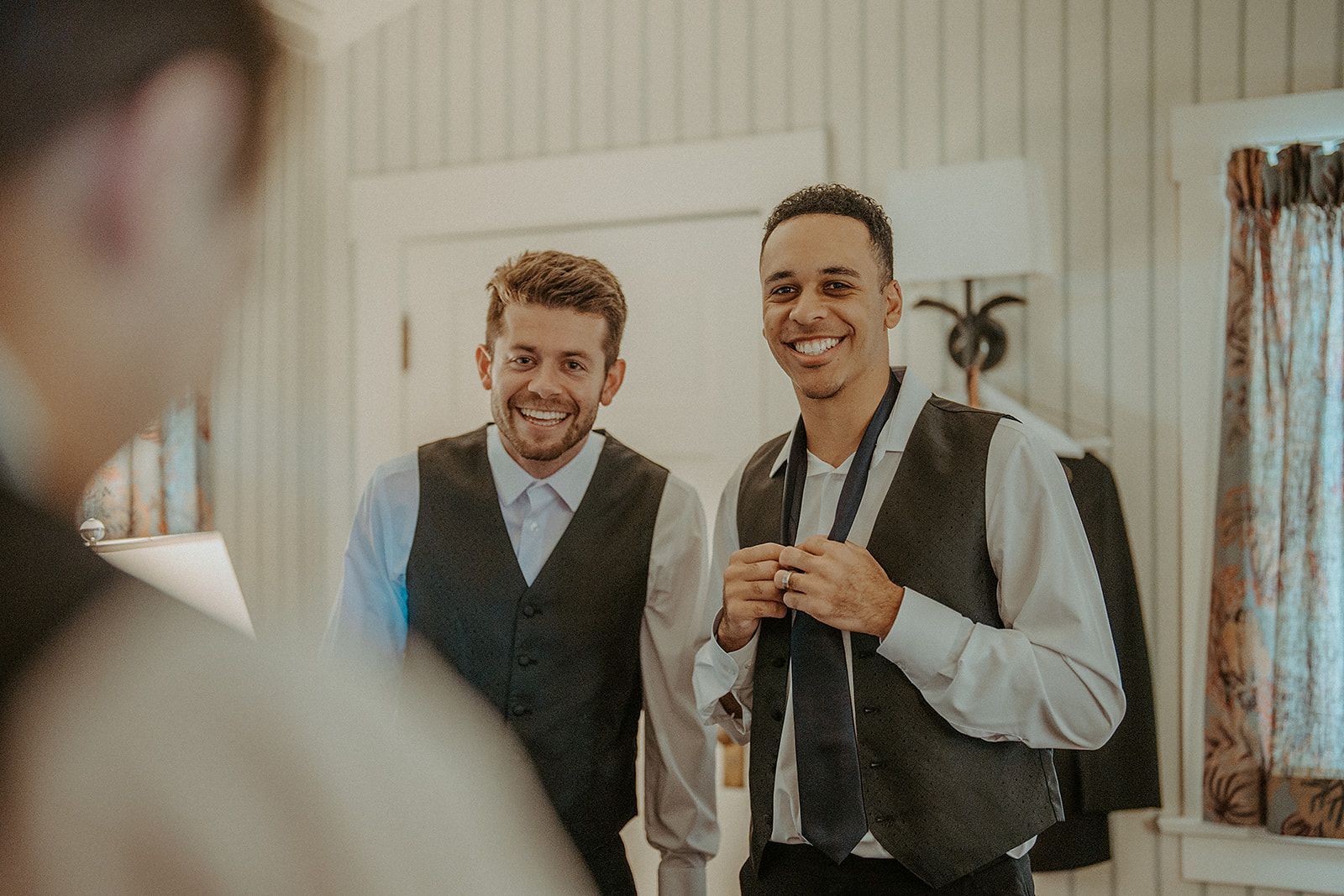 Two men are standing next to each other in a room and smiling.