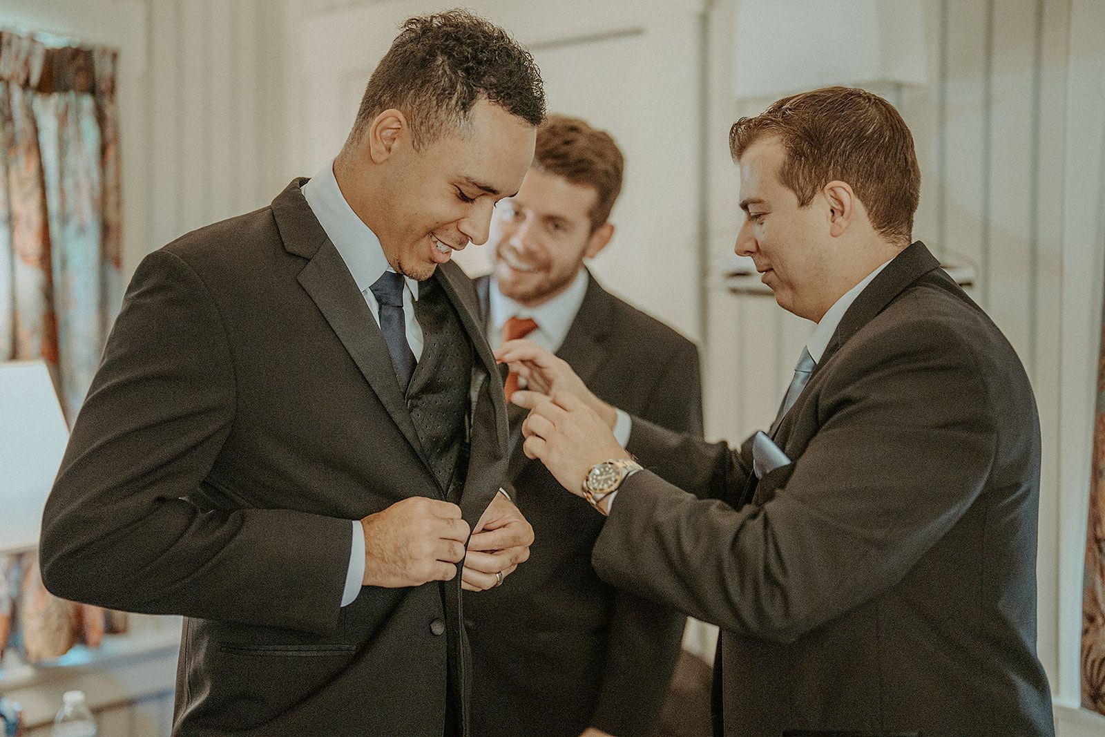 A groom and his groomsmen are helping the groom get ready for his wedding.