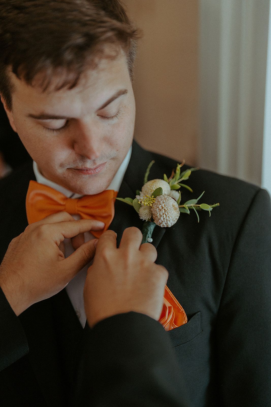 A man in a suit and bow tie is getting ready for his wedding.