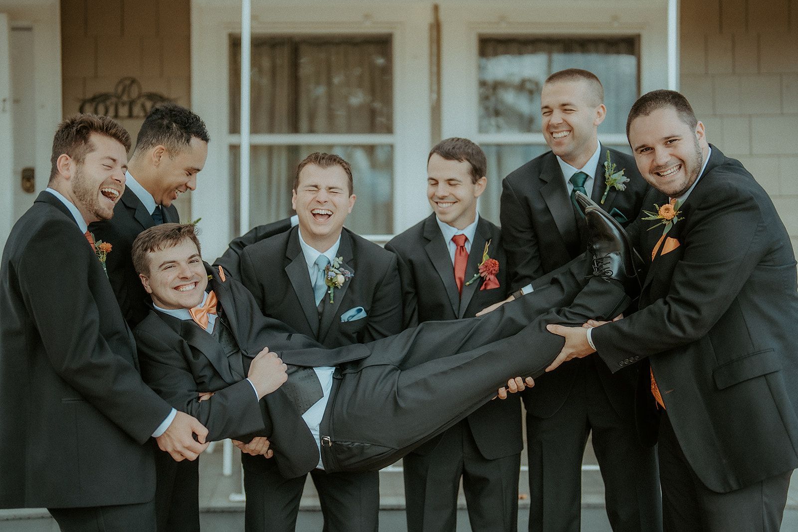 A group of men in suits are holding a man in their arms.