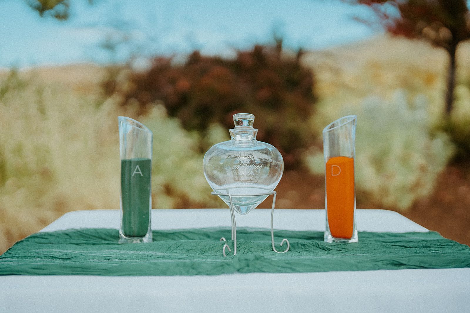 A table with three glasses and a bottle of sand on it.