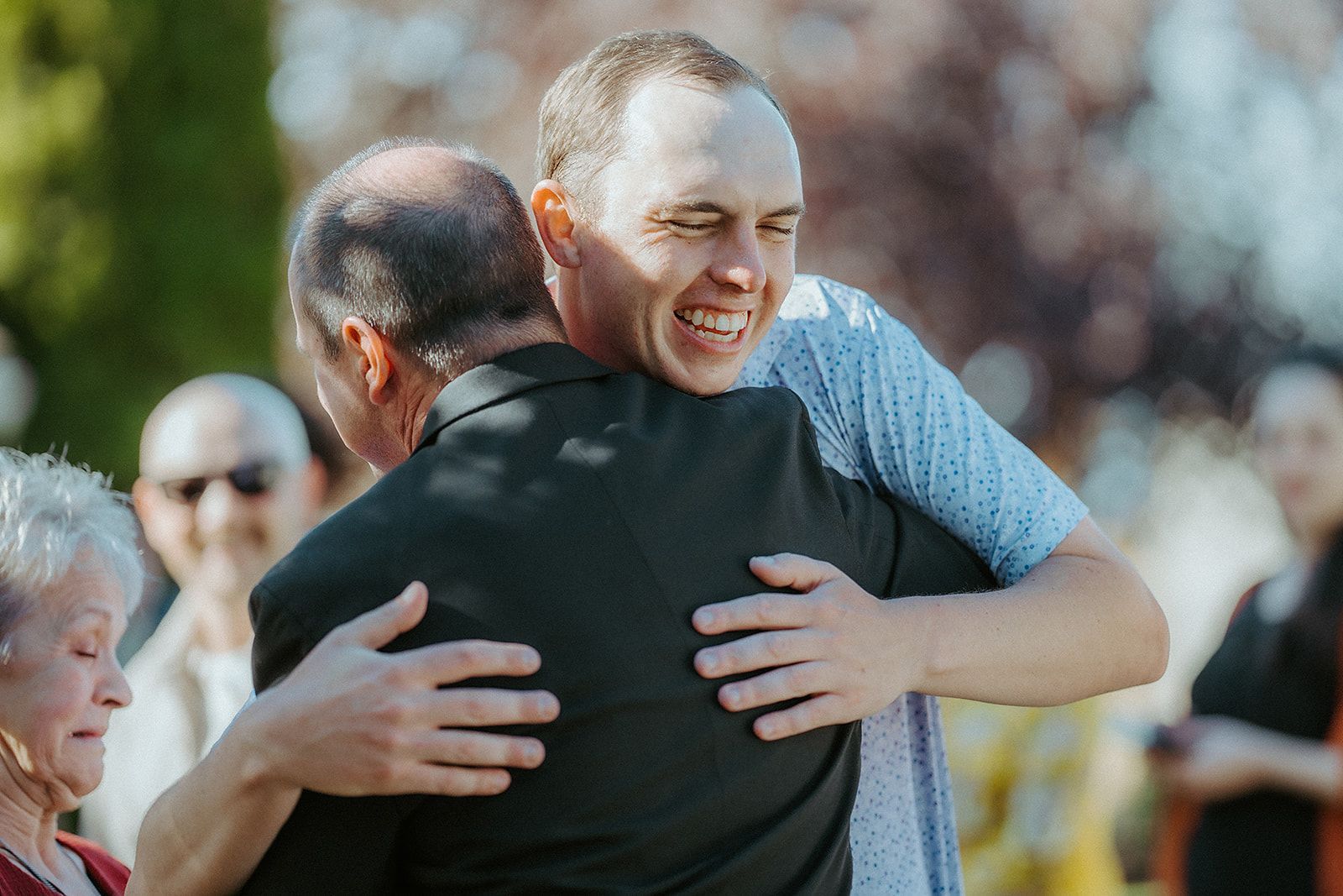 Two men are hugging each other and smiling.