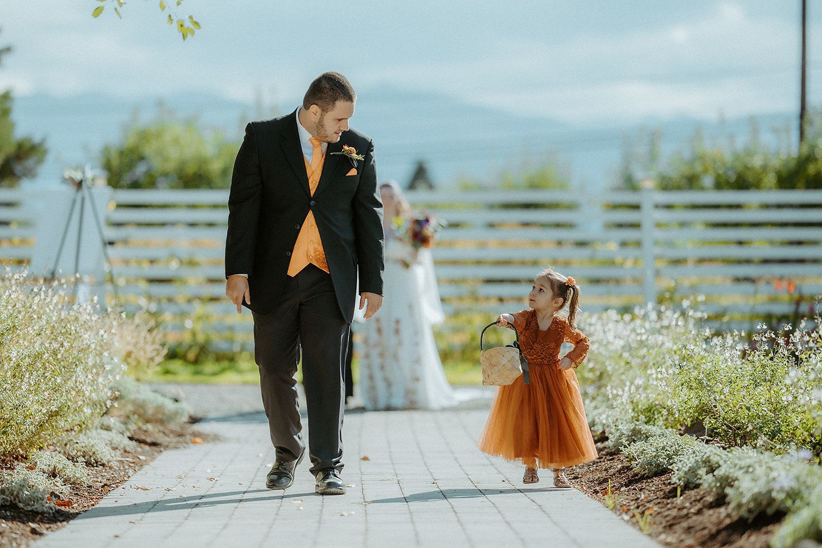 A groomsman is walking down the aisle with a flower girl.