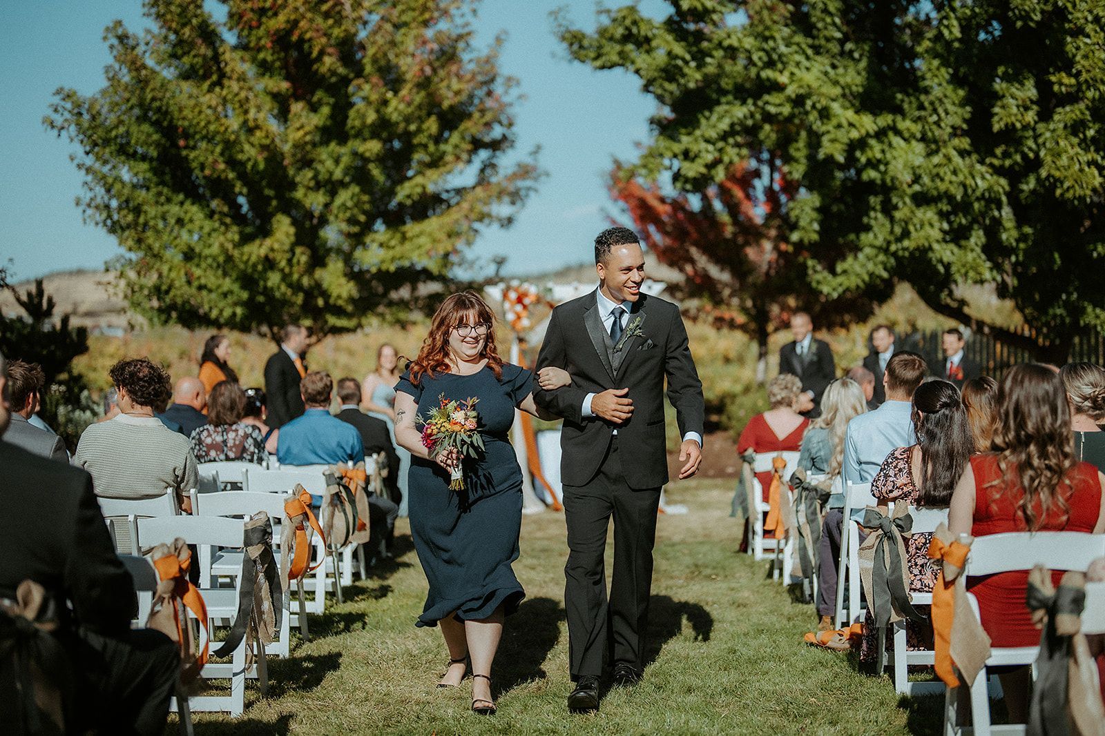 A groomsman and a bridesmaid are walking down the aisle at a wedding.