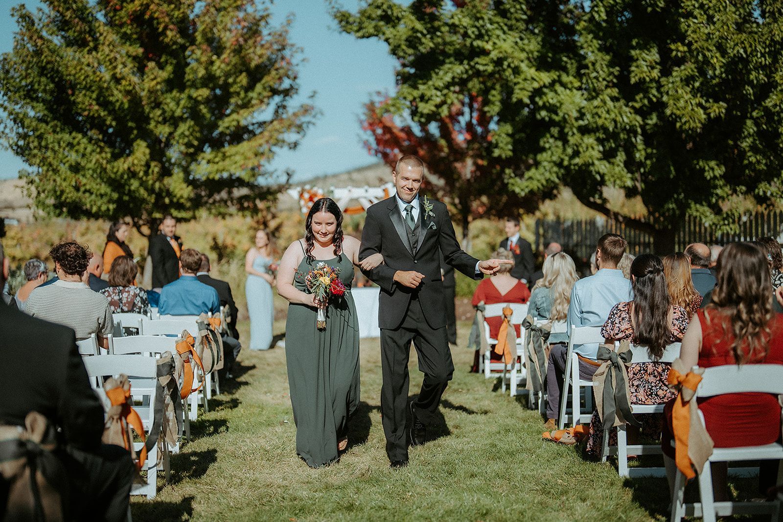A groomsman and a bridesmaid are walking down the aisle at a wedding.