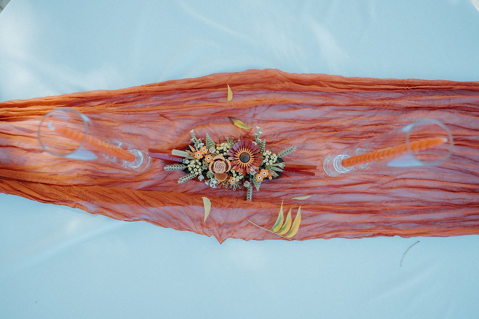A wooden table with glasses and flowers on it.