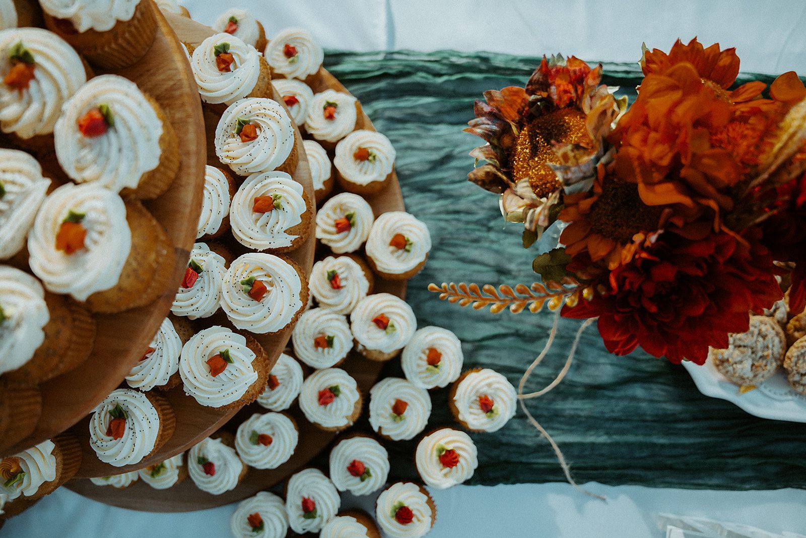 A wooden tray filled with cupcakes and flowers on a table.
