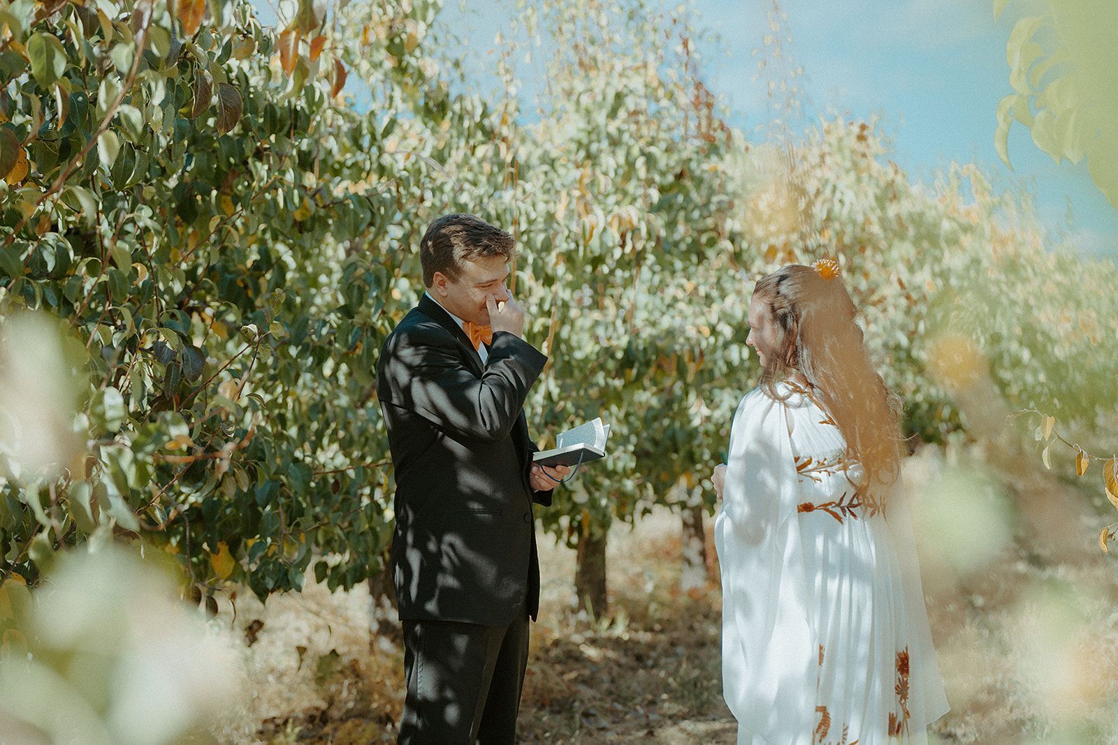 A bride and groom are standing next to each other in a field.
