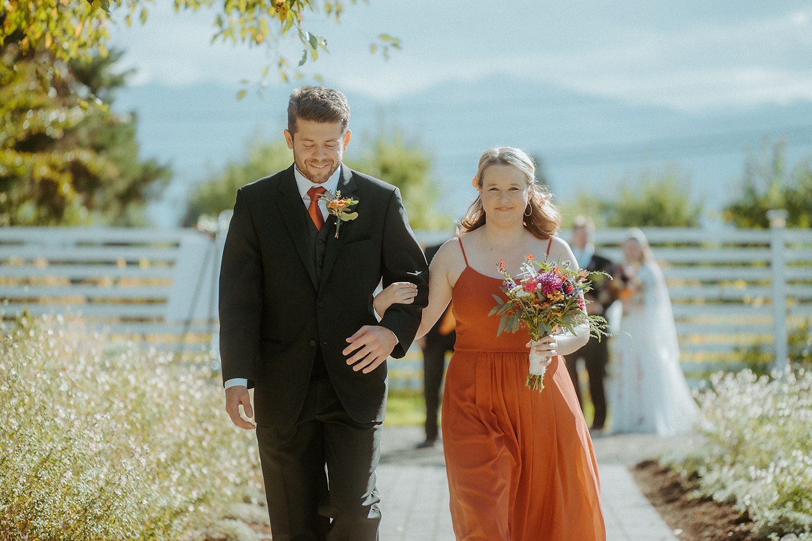 A groomsman and a bridesmaid are walking down the aisle at a wedding.