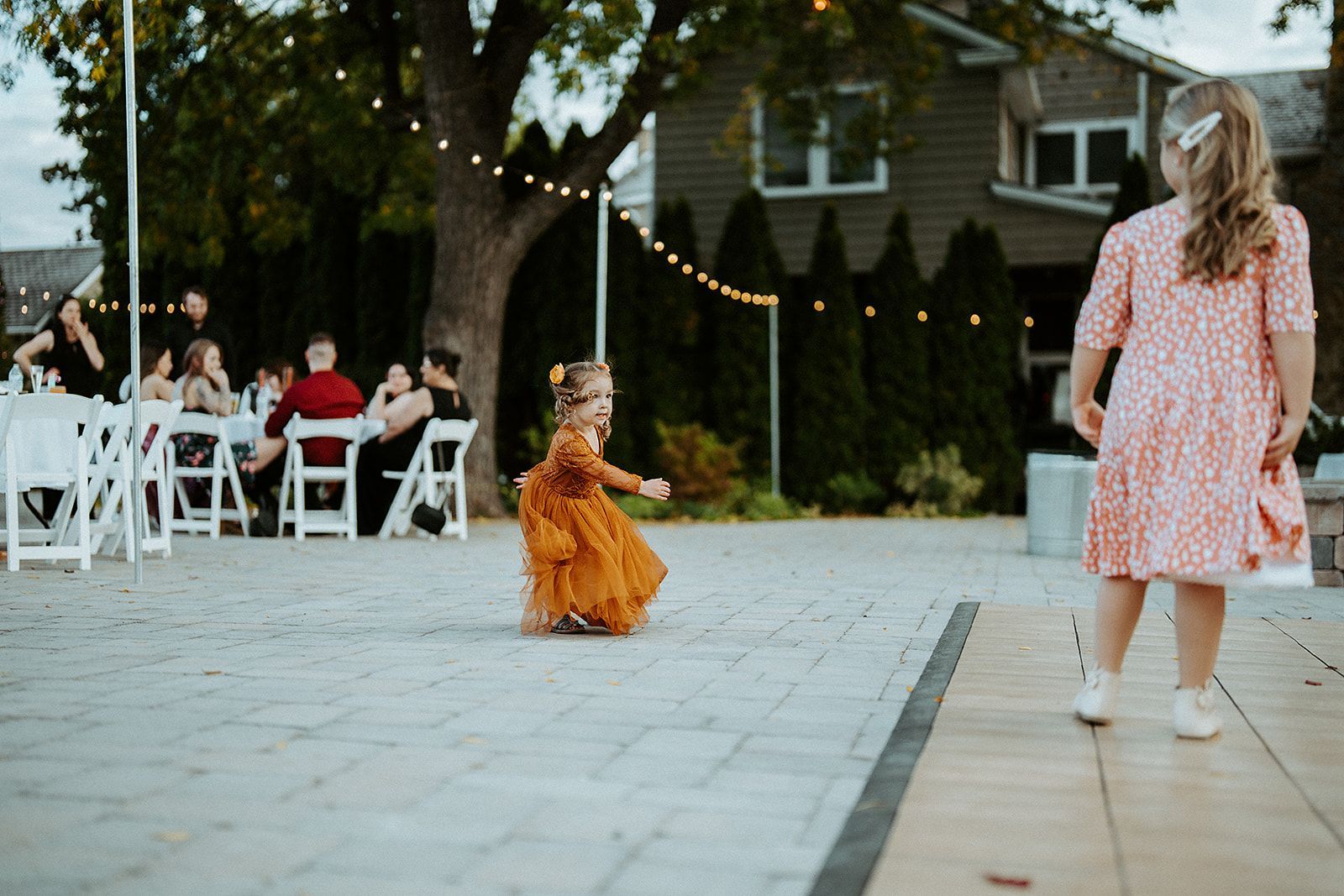 A little girl in a dress is running towards a woman in a pink dress.