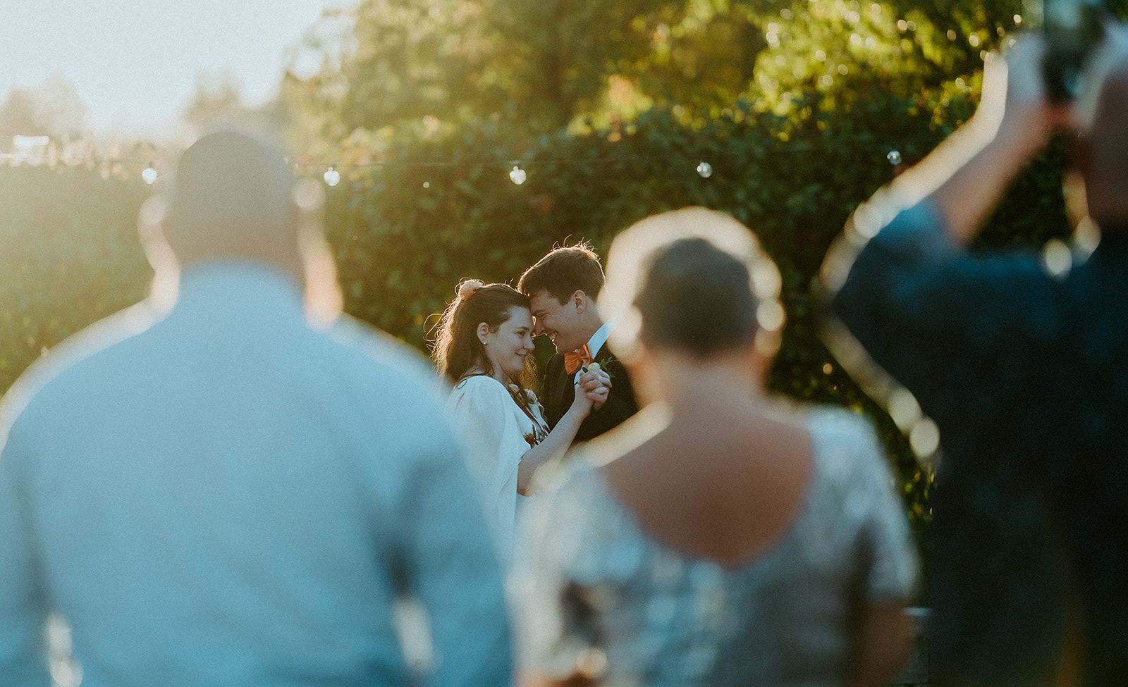 A man is taking a picture of a bride and groom dancing at a wedding reception.