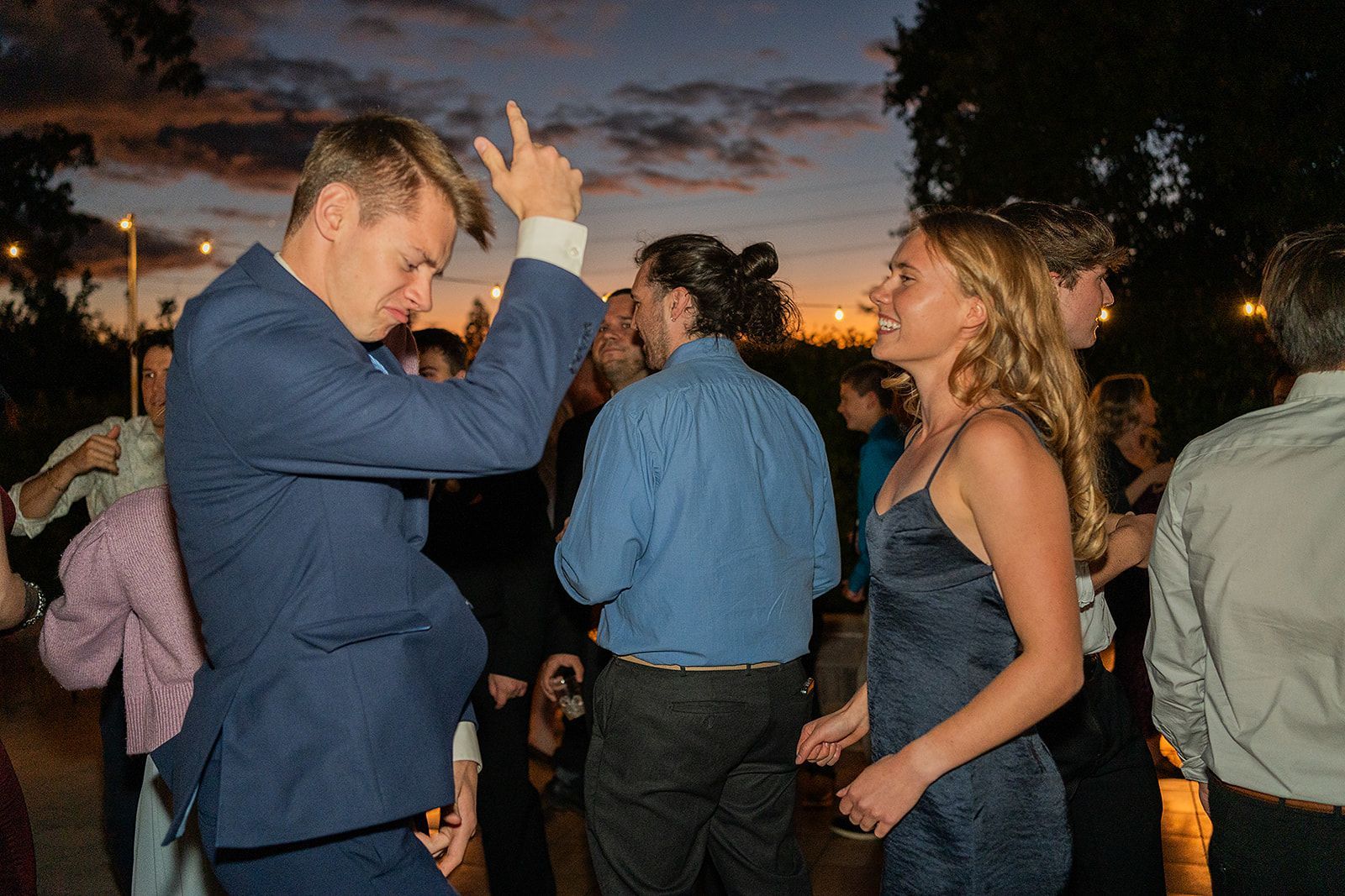 A man in a suit is dancing with a woman in a dress at a party.