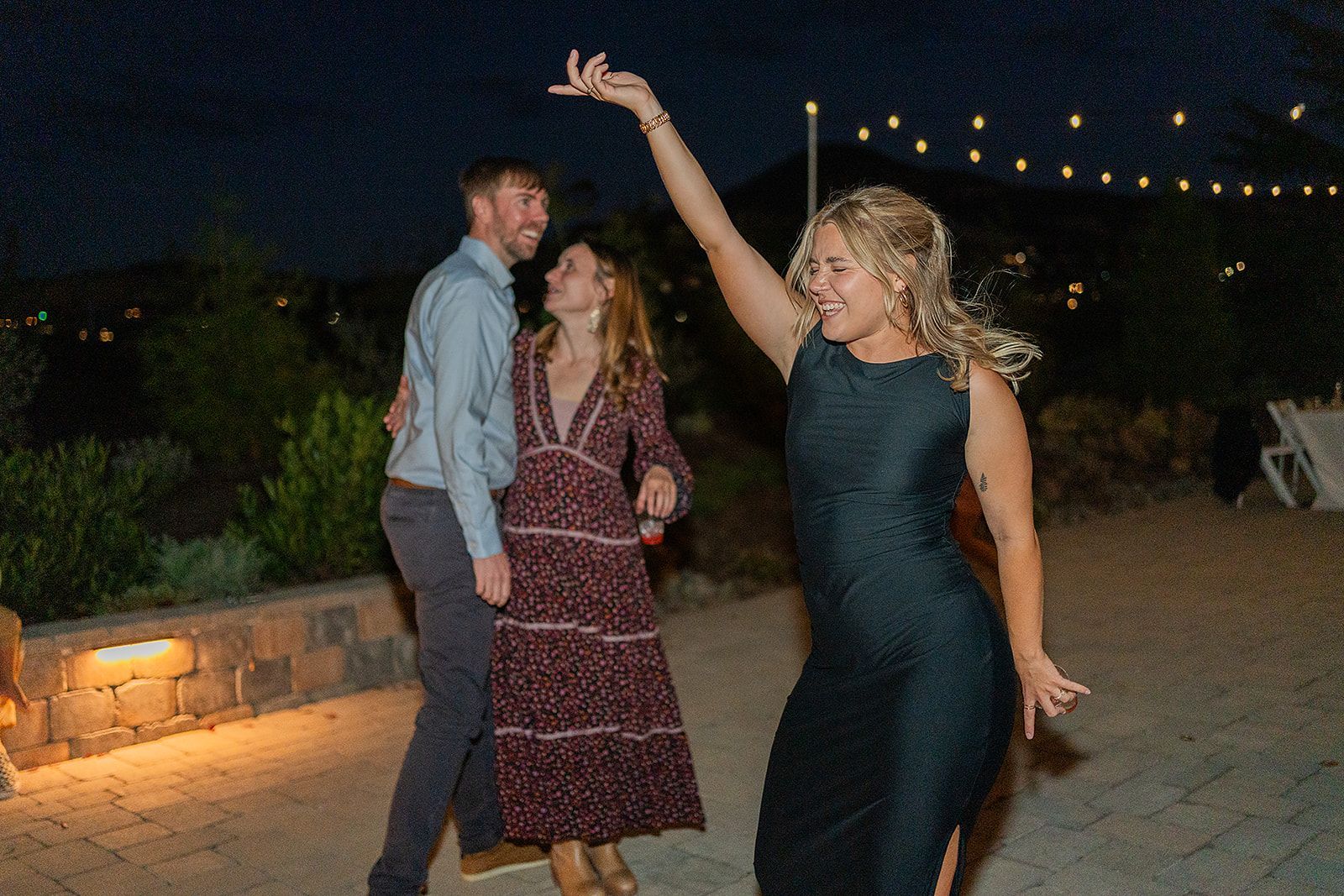 A woman in a dress is dancing with a man and a woman at a wedding reception.