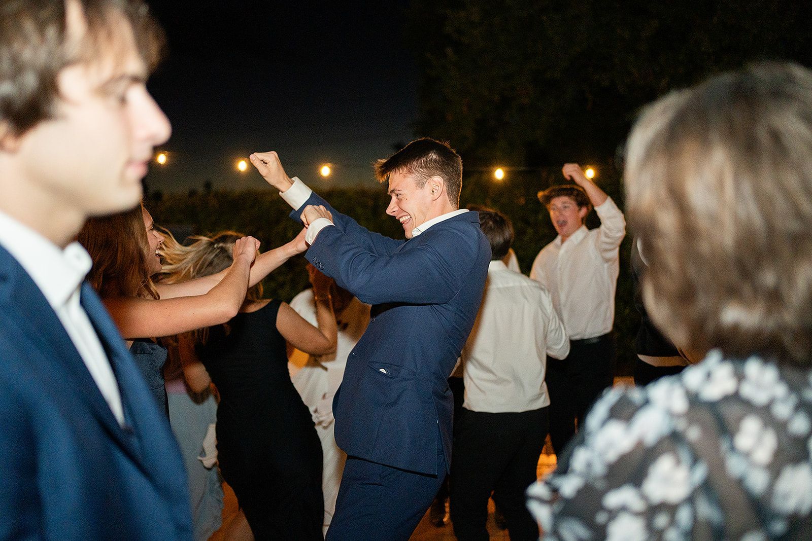 A group of people are dancing at a wedding reception.