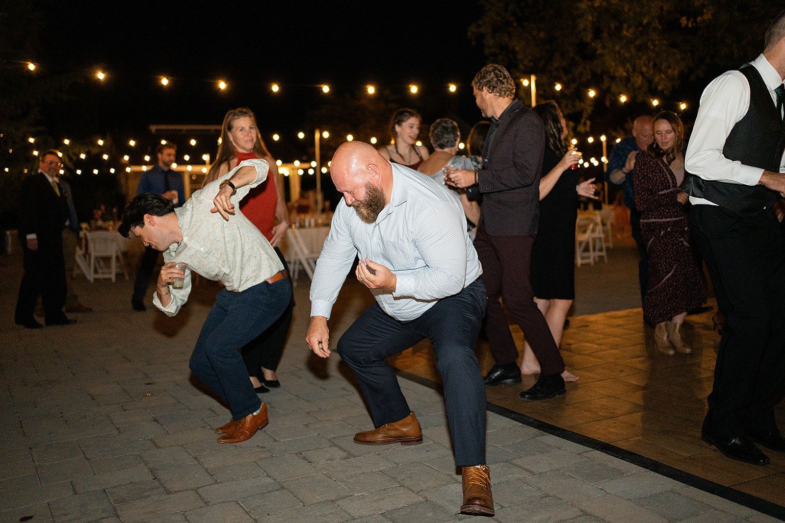 A group of people are dancing at a wedding reception.