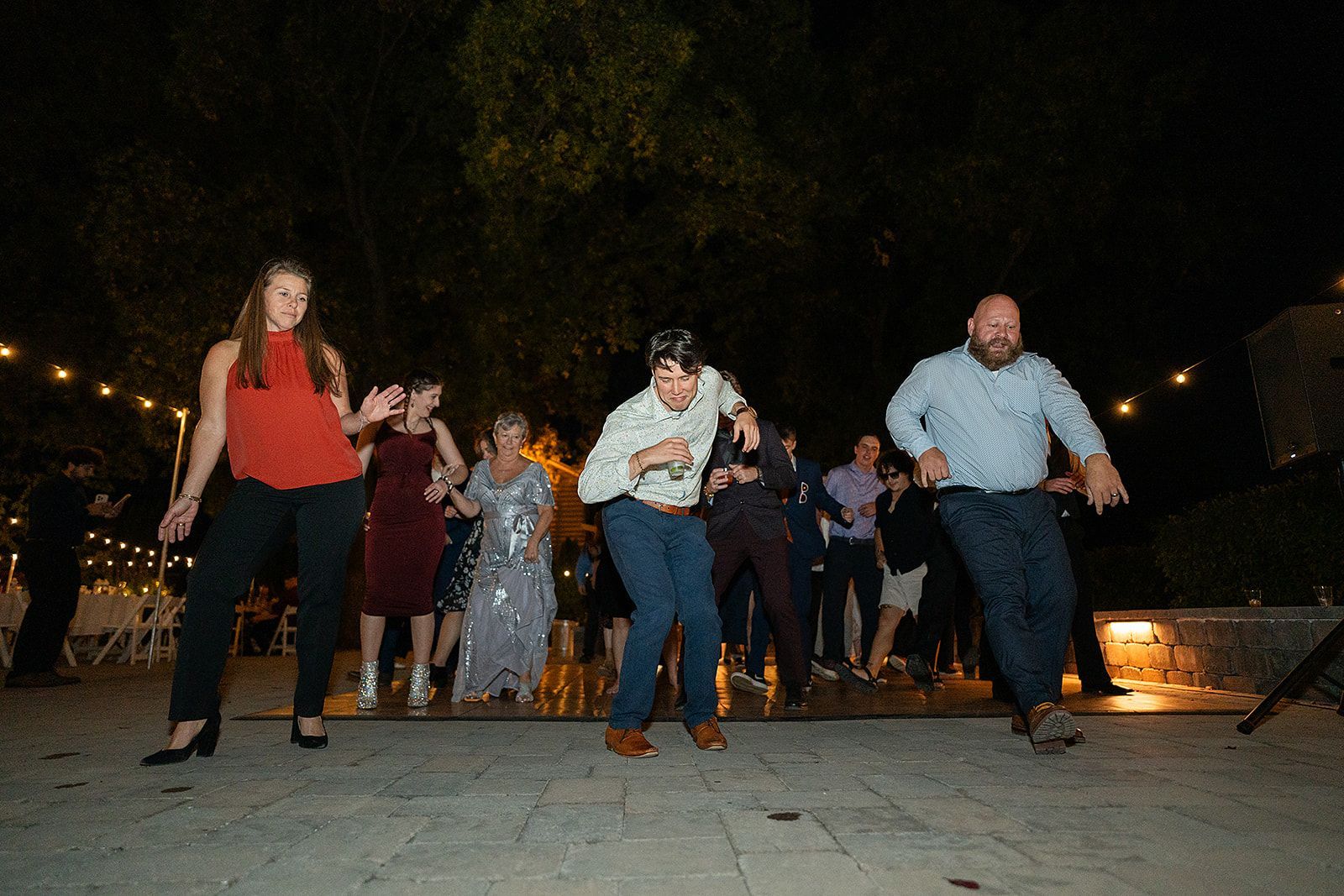 A group of people are dancing on a dance floor at a wedding reception.