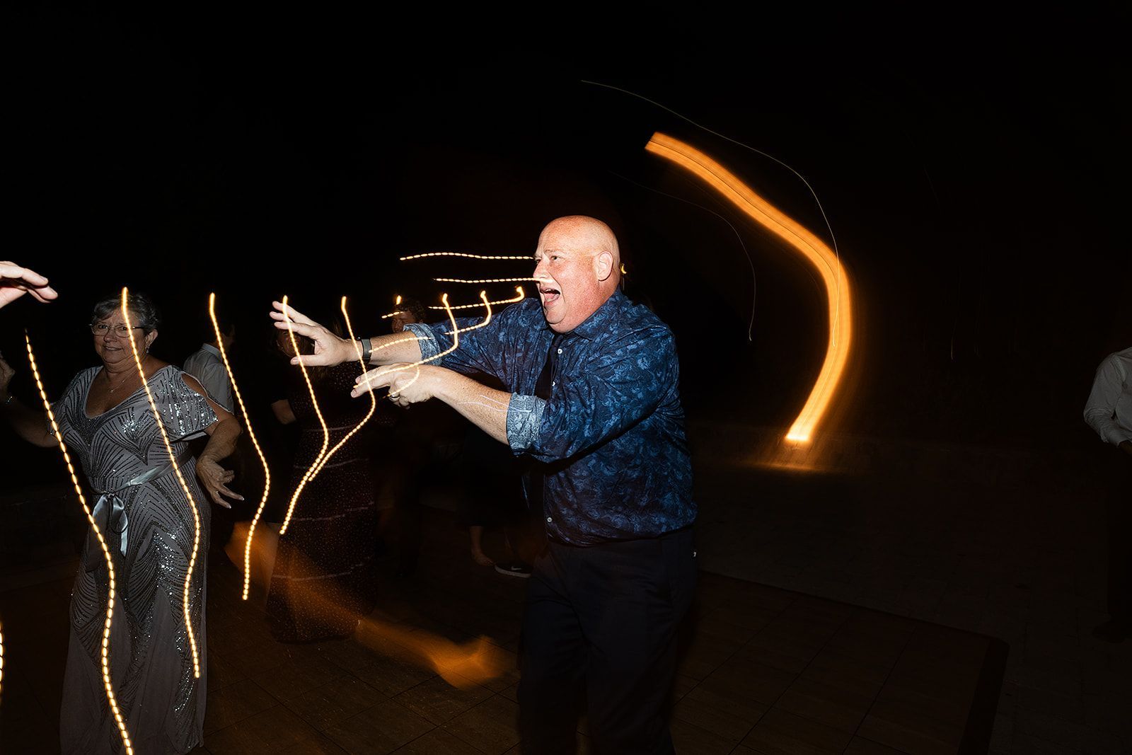 A man and a woman are dancing at a wedding reception at night.