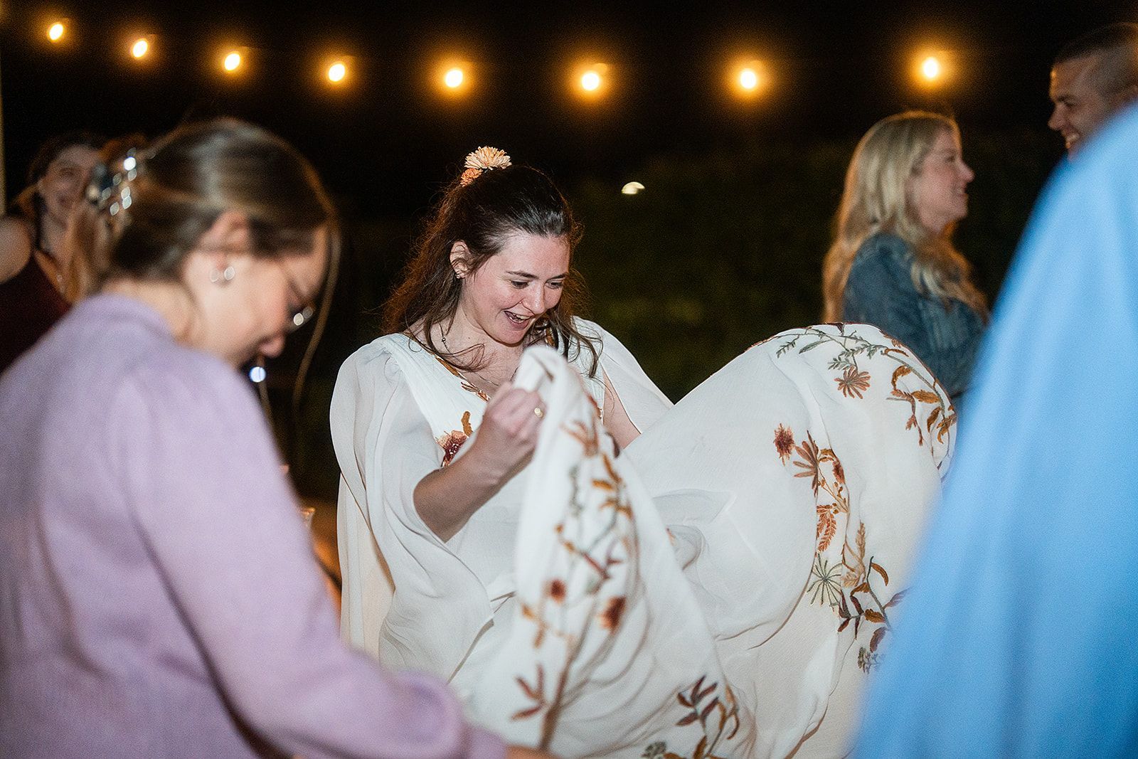 A woman in a white dress is dancing with a group of people.