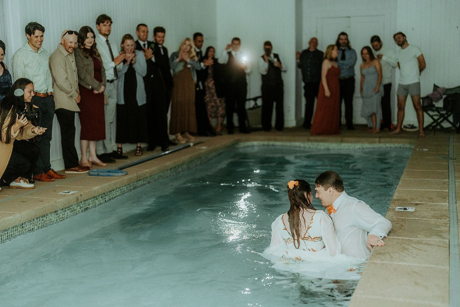 A group of people are standing around a swimming pool.
