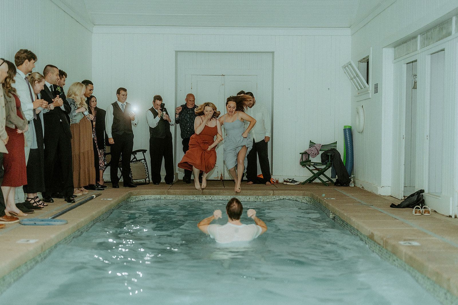 A group of people are standing around a swimming pool.
