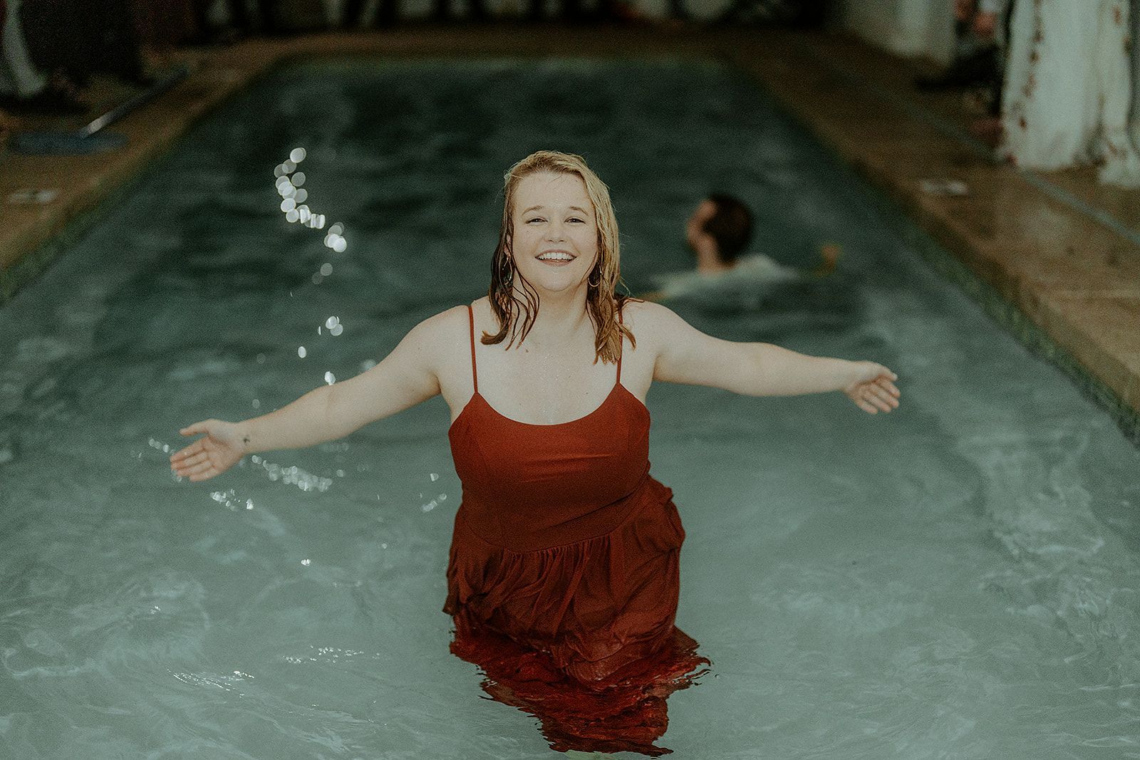 A woman in a red dress is standing in a swimming pool.