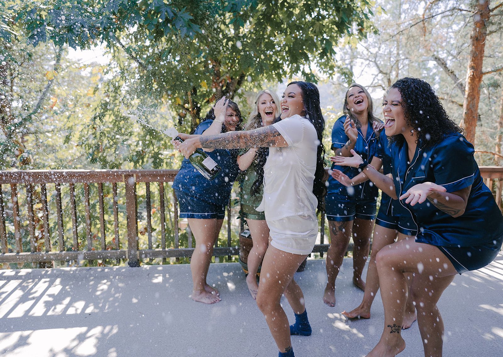 A bride and her bridesmaids are dancing on a deck.