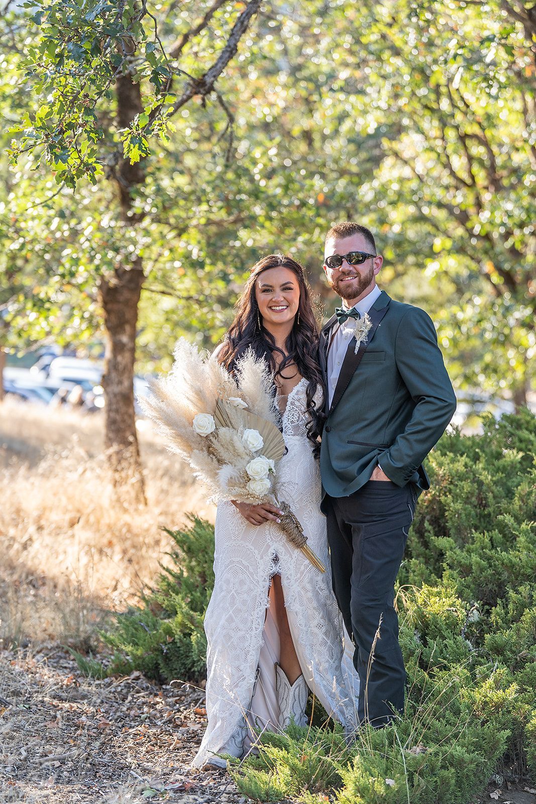 A bride and groom are posing for a picture in the woods.