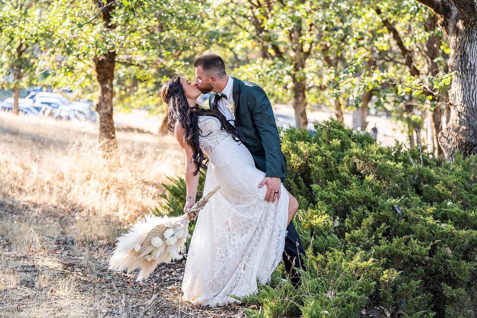 A bride and groom are kissing in the woods.