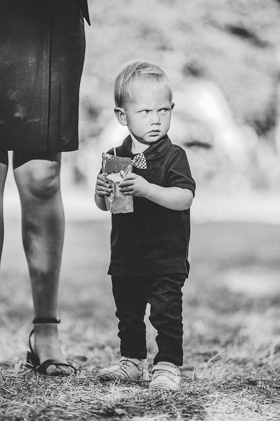 A black and white photo of a little boy walking next to a woman.