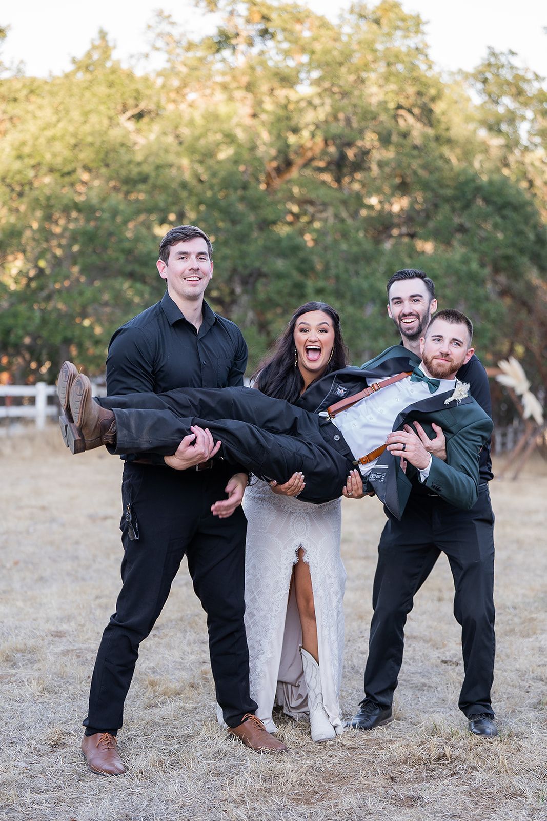 A man is carrying a woman in his arms in a field.