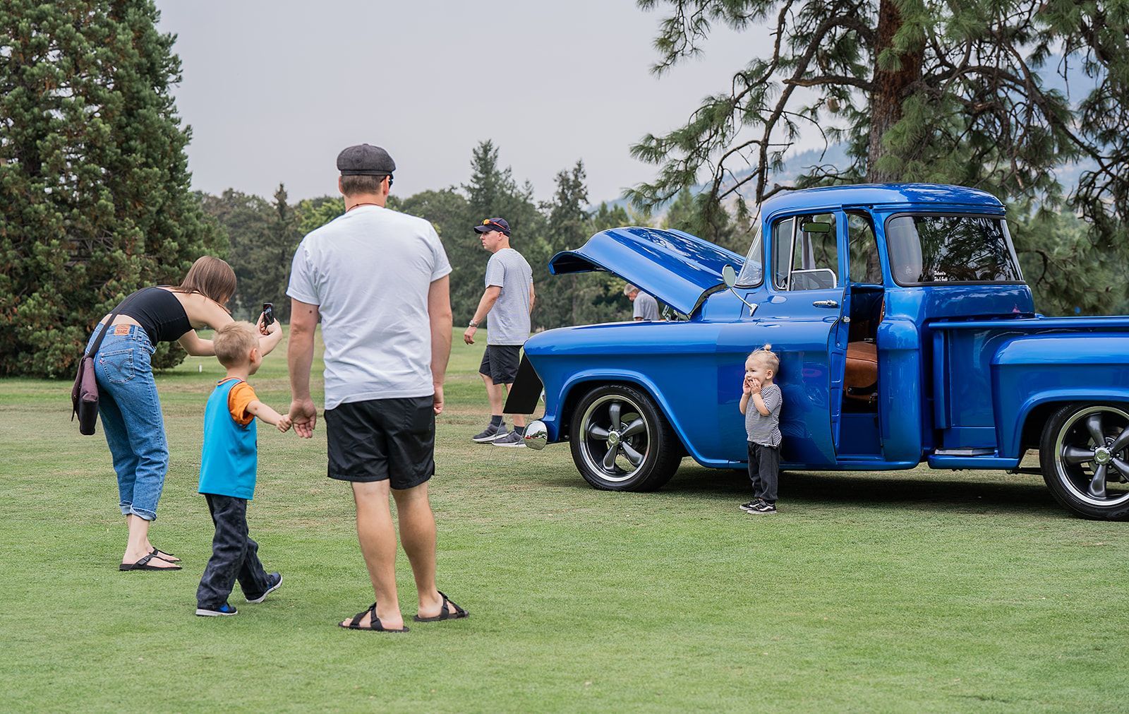 A group of people are standing in front of a blue truck.