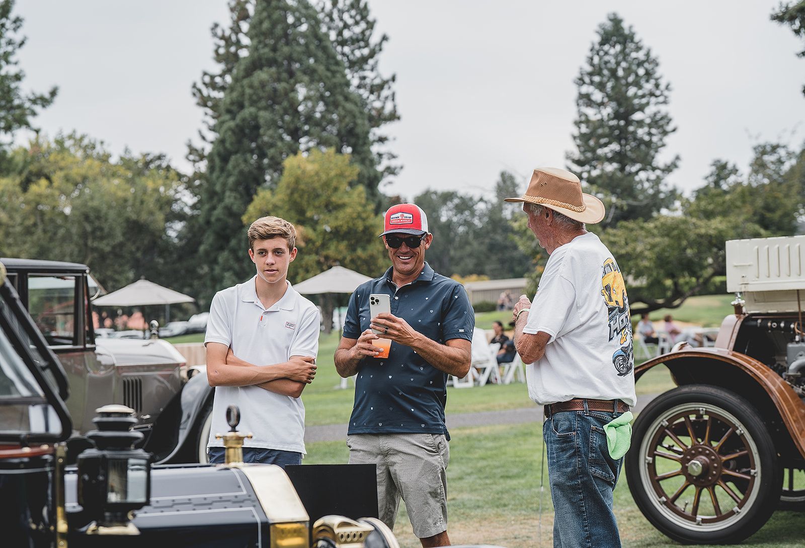 A group of men are standing in front of an old car.