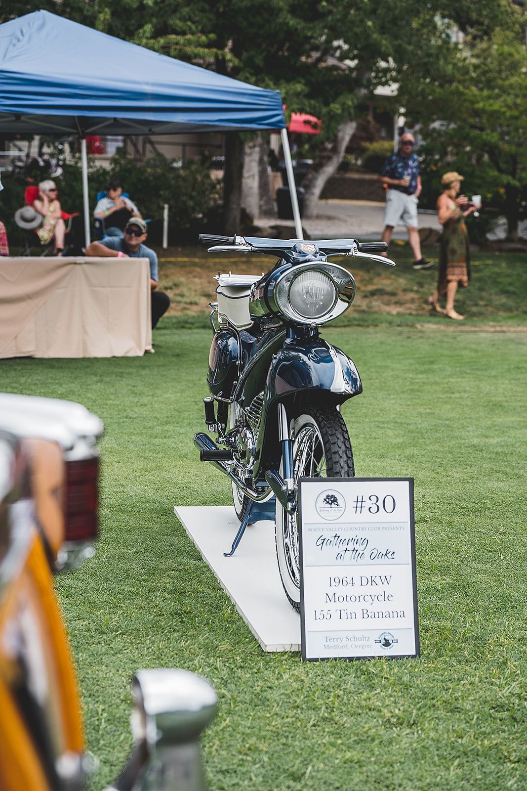 A motorcycle is parked in the grass next to a sign.