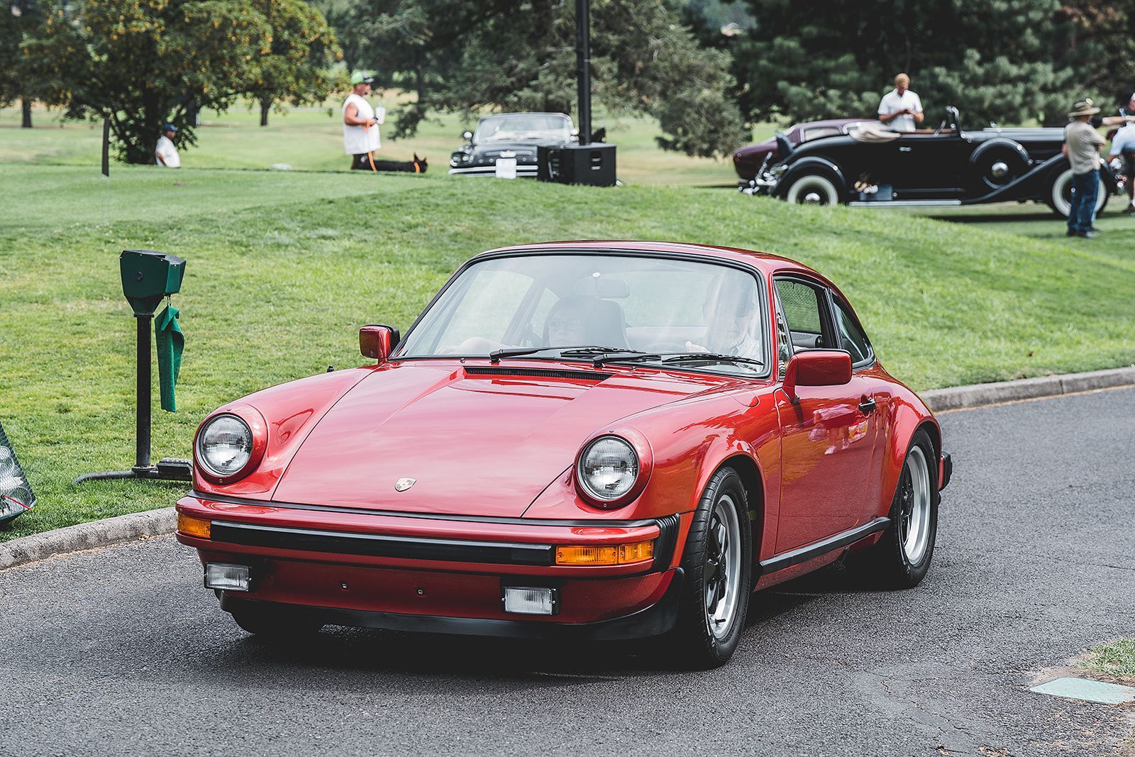 A red porsche is parked on the side of the road.