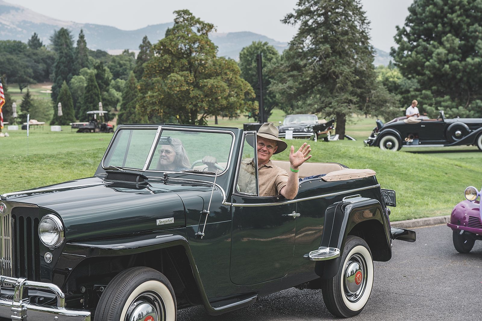 A man in a hat is sitting in a black convertible jeep.