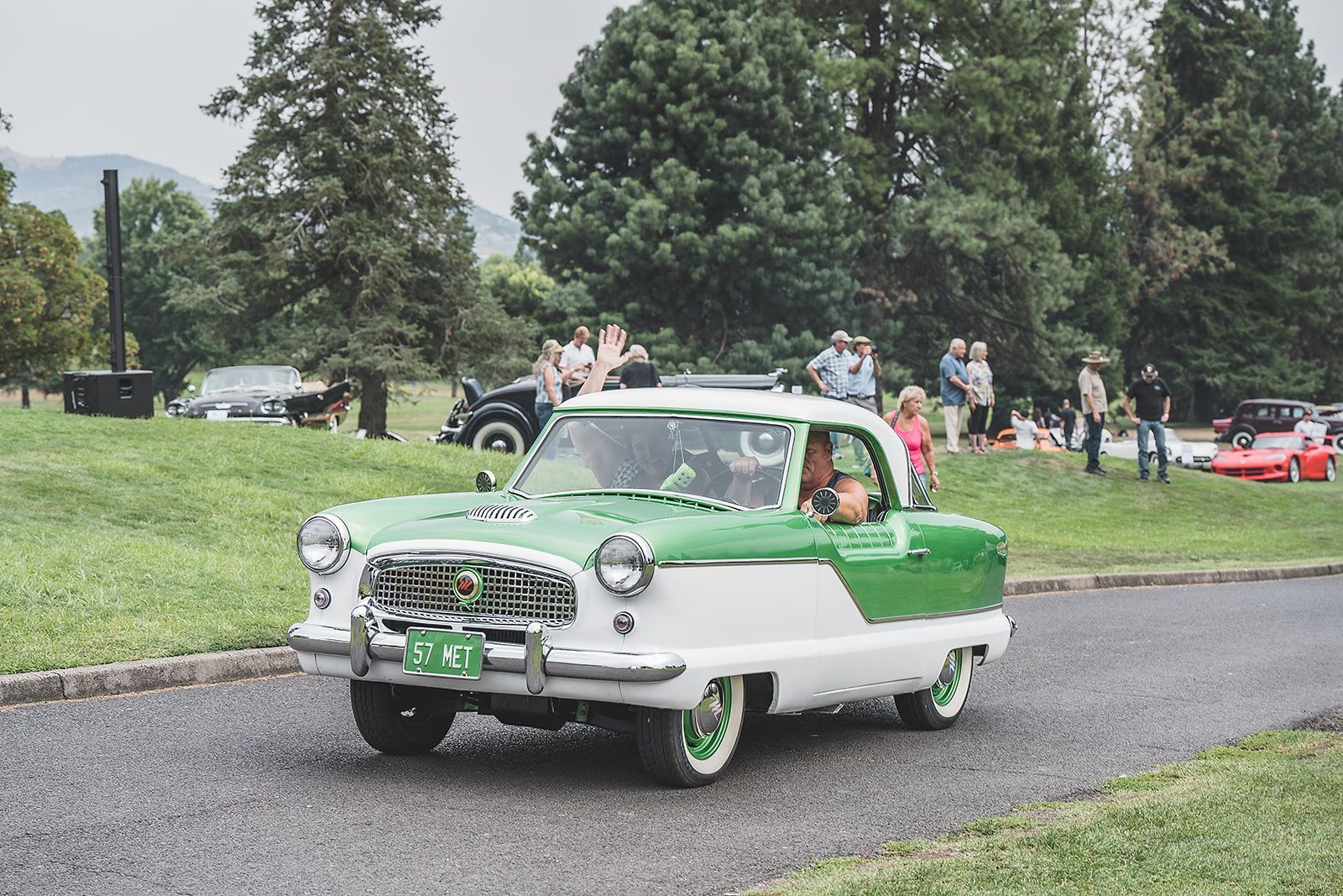 A green and white car is driving down a road.