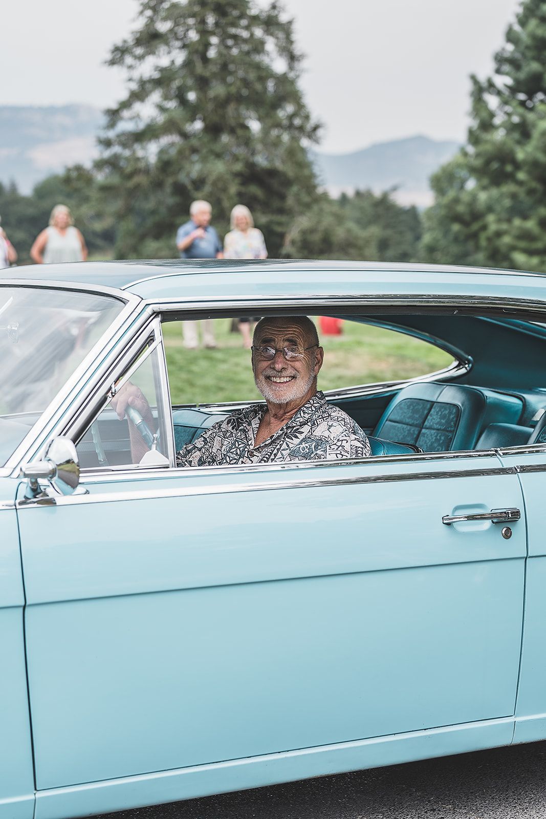 A man is sitting in the driver 's seat of a blue car.