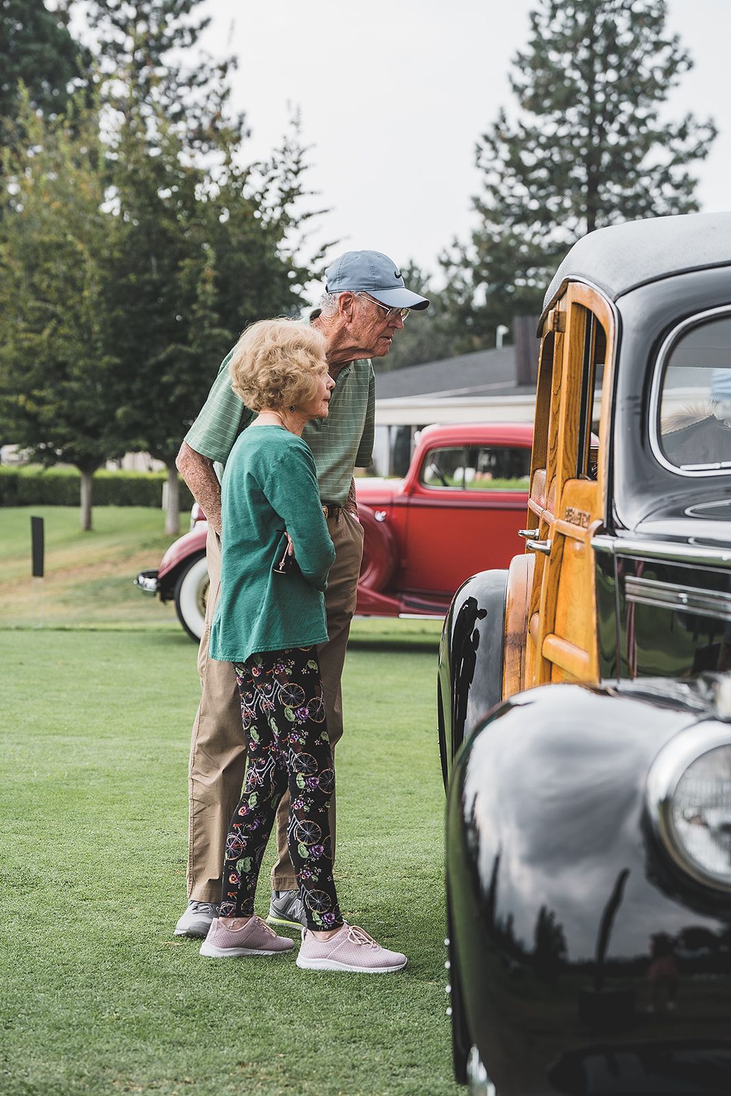 An elderly couple is looking at an old car at a car show.