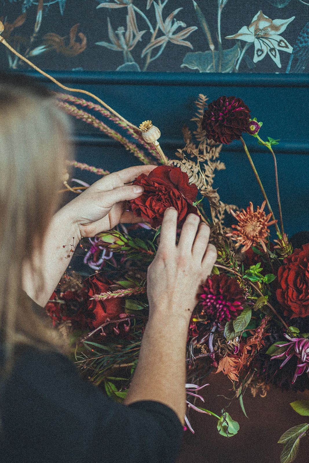 A woman is arranging flowers on a table.
