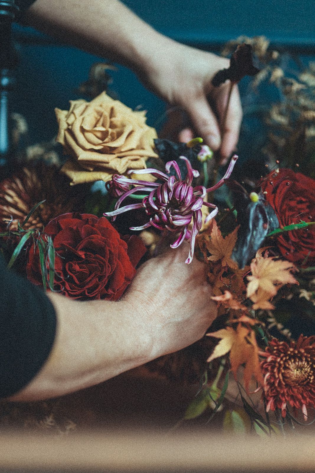 A person is arranging flowers in a vase on a table.