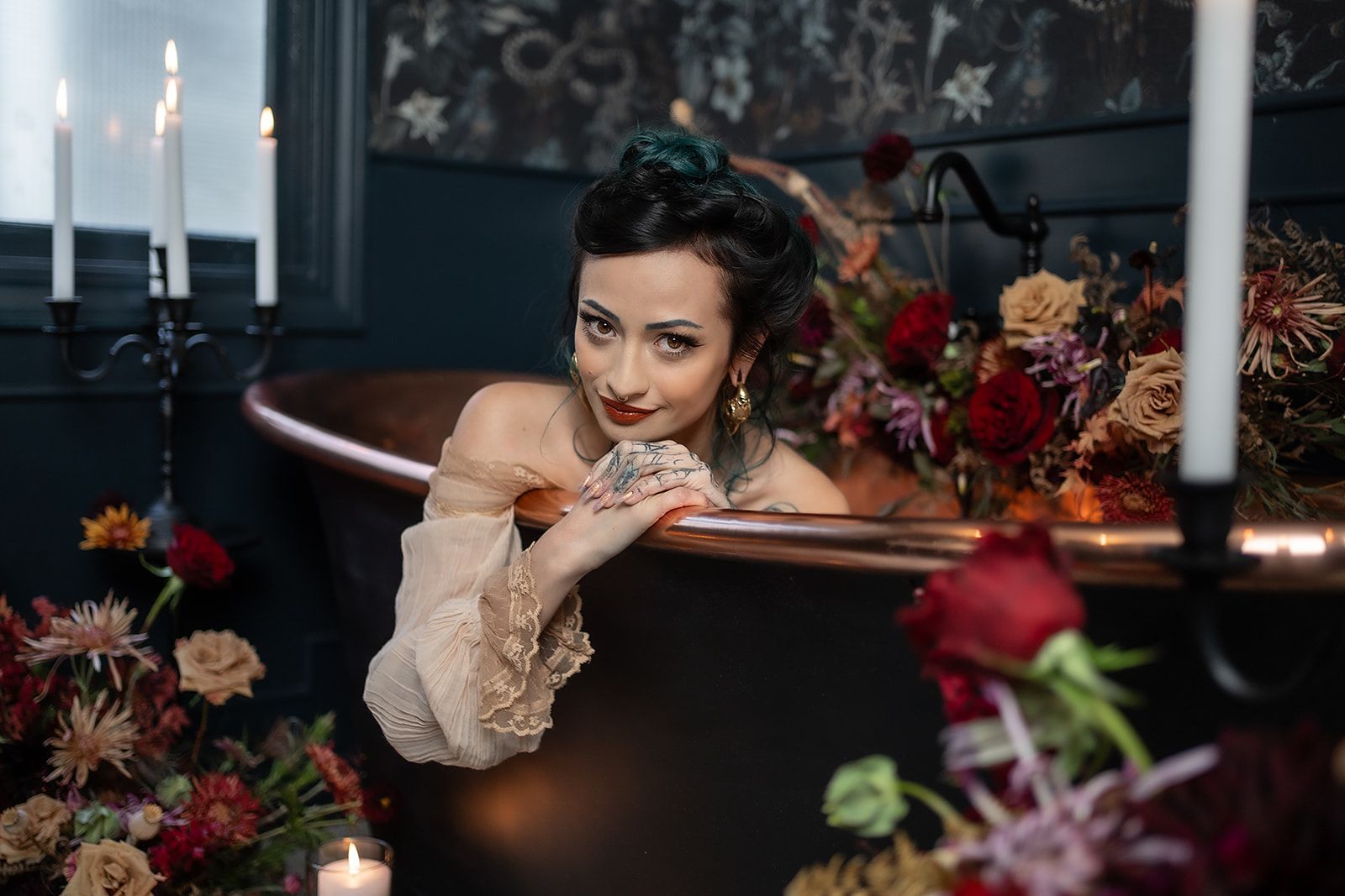 A woman is sitting in a bathtub surrounded by flowers and candles.